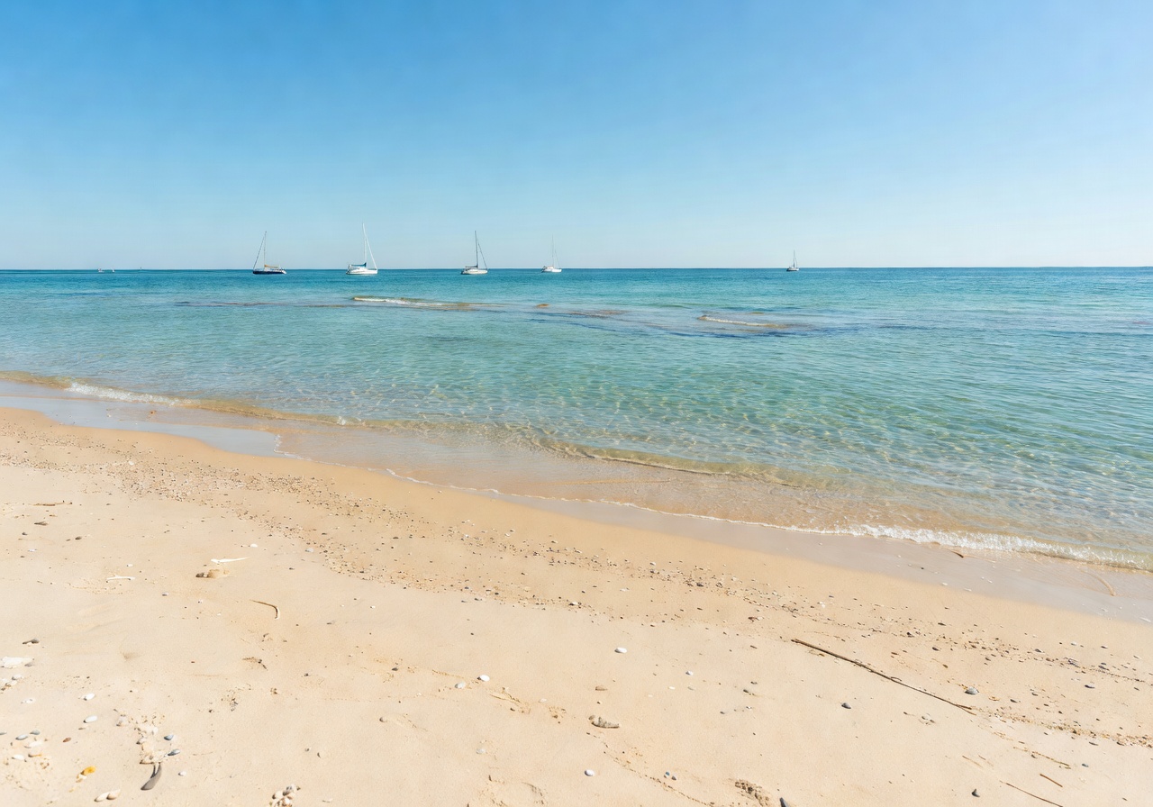 Sandy Finnish beach with turquoise water and distant sailboats during summer